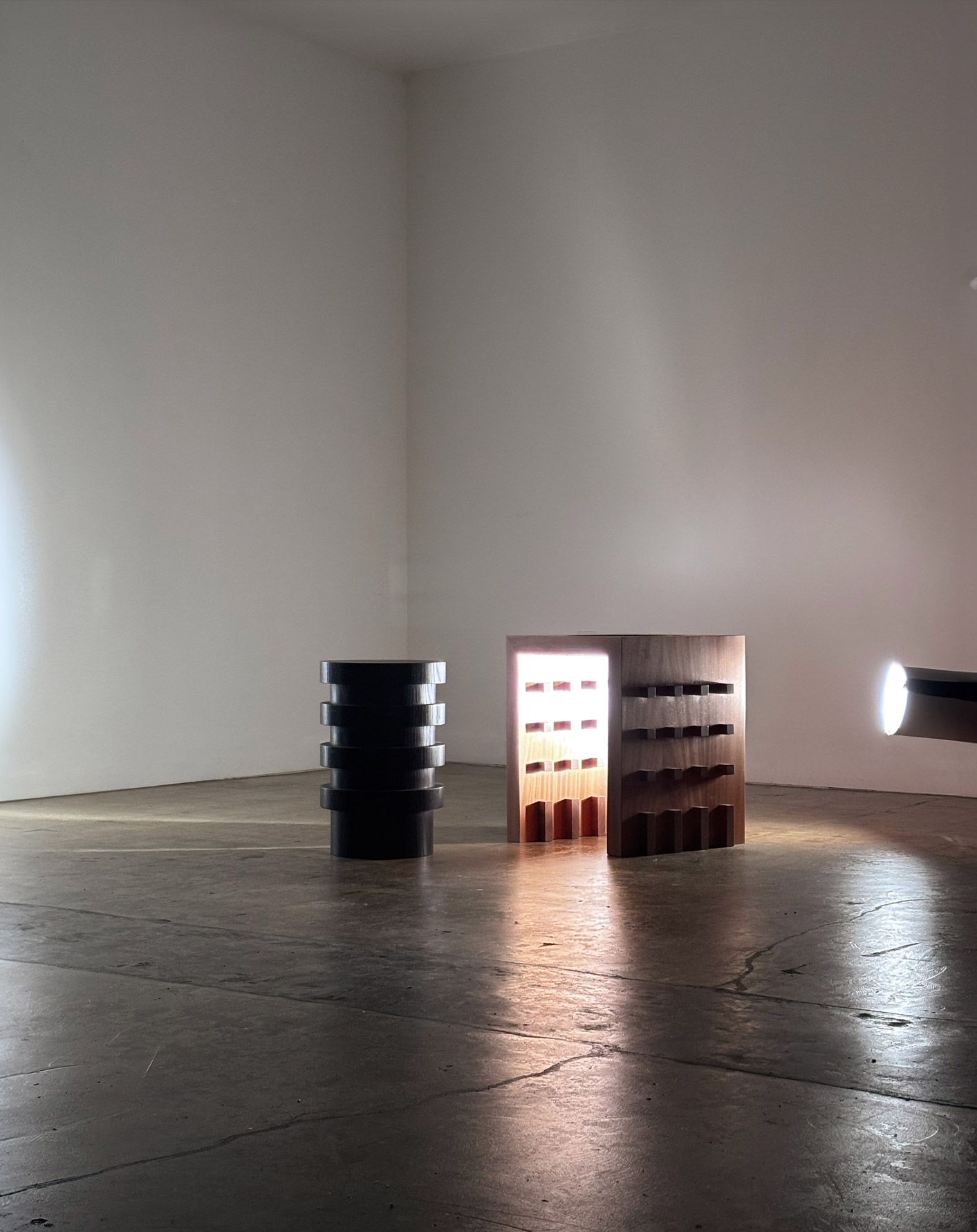 An ebonized ash end table and a natural finish sapele end table lit from the side with a bright light